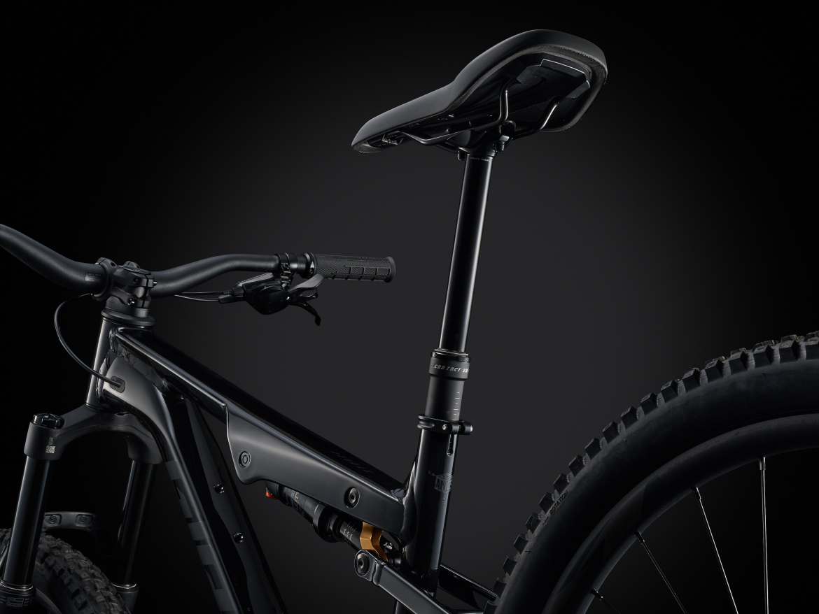 Close-up of a modern mountain bike showcasing the black frame, handlebars, and a dropper seat post against a dark background. The image highlights the bike's sleek design and attention to detail.