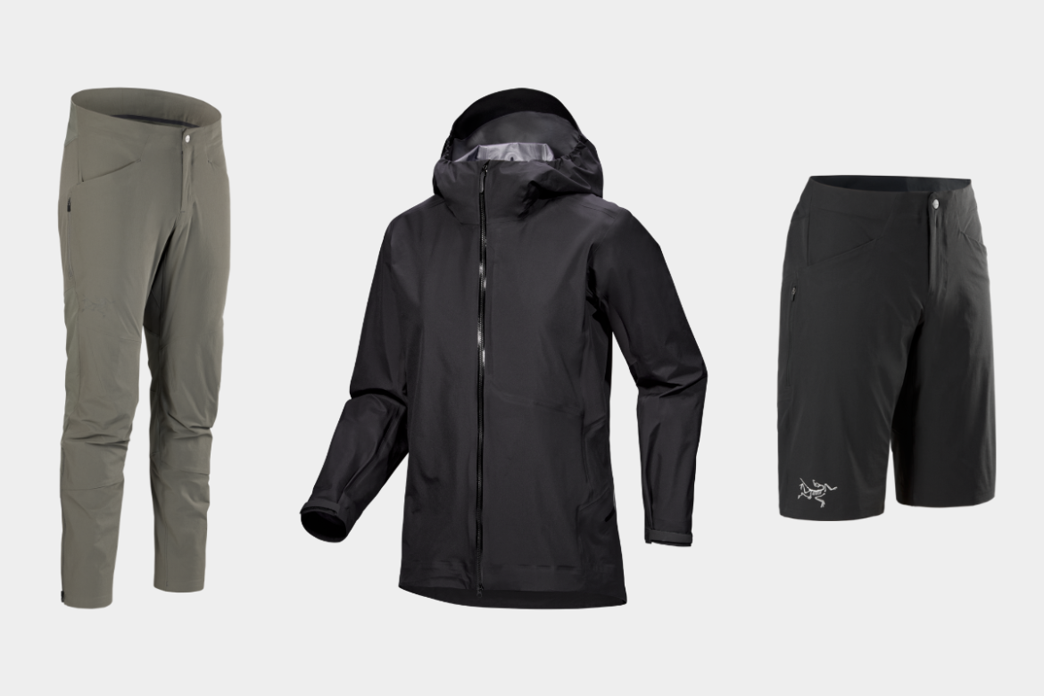 A collection of outdoor clothing including a black waterproof jacket in the center, light gray pants on the left, and black shorts on the right, all displayed against a plain white background.