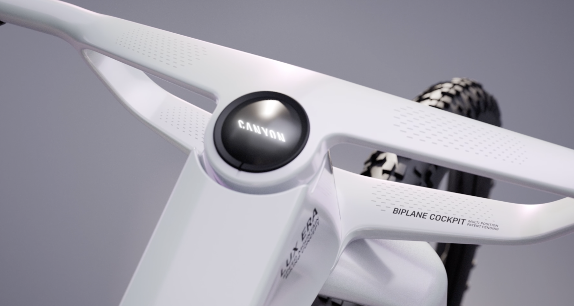 Close-up of a white bicycle handlebar with a modern design, featuring the word "CANYON" prominently displayed on the central circular component. The handlebar is labeled with "BIPLANE COCKPIT" and includes textured grip sections, showcasing a sleek, aerodynamic aesthetic suitable for high-performance cycling.