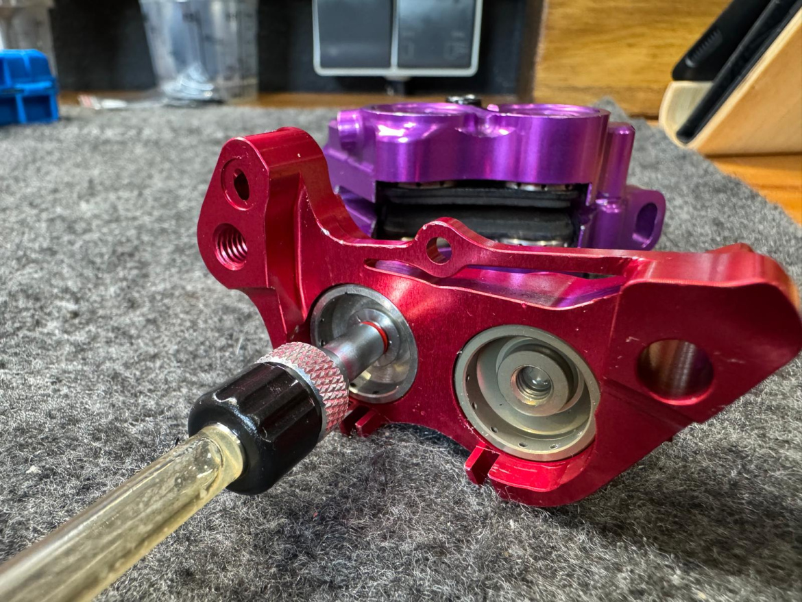 A close-up view of a red Hustok Sprint caliper receiving DOT fluid