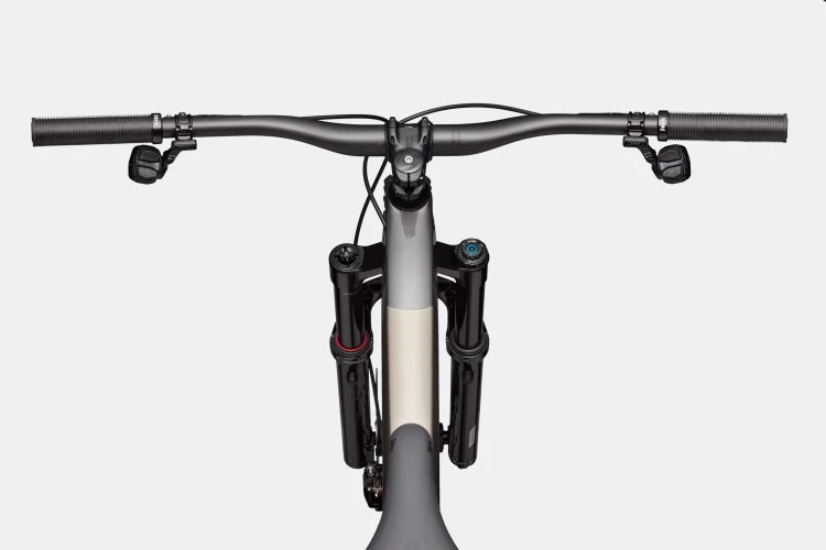Alt text: Close-up view of a mountain bike's handlebars and front suspension, showcasing black grips, brake levers, and adjustment knobs on the suspension. The image has a clean, white background.