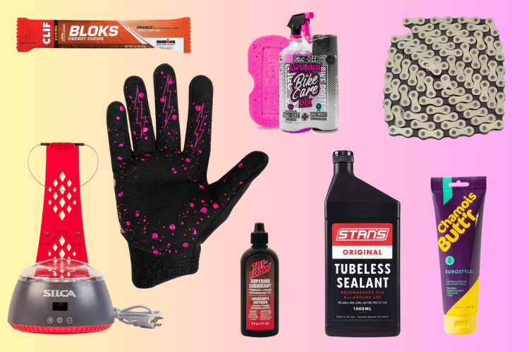 A collection of cycling accessories on a gradient background, including a Clif energy chew, a bike cleaning spray and sponge, a black glove with pink accents, a silicone bicycle tire pump, a bottle of lubricant, a container of tubeless sealant, a bicycle chain, and chamois cream for comfort during rides.