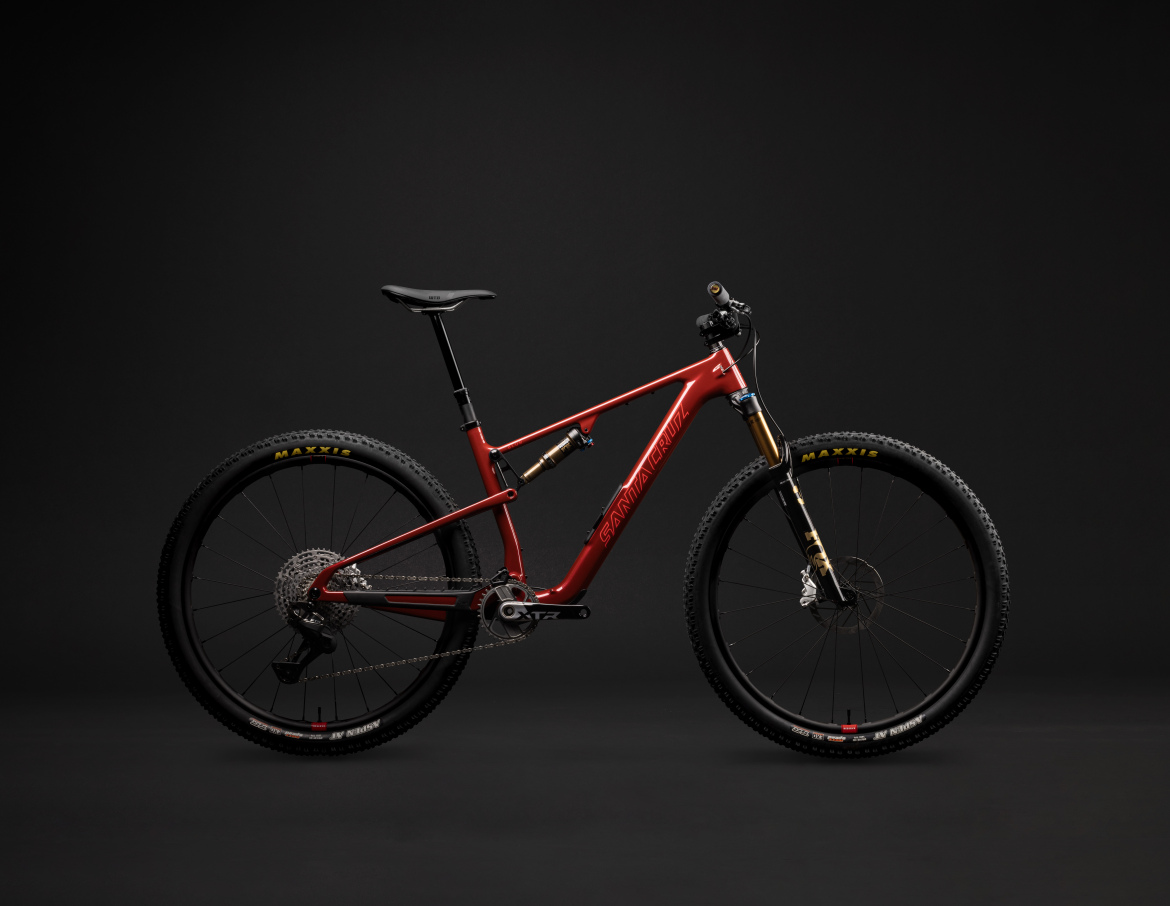 A mountain bike with a sleek red frame, featuring high-quality components, large black tires with yellow lettering, and a modern design. The bike is set against a dark background, highlighting its details and craftsmanship.
