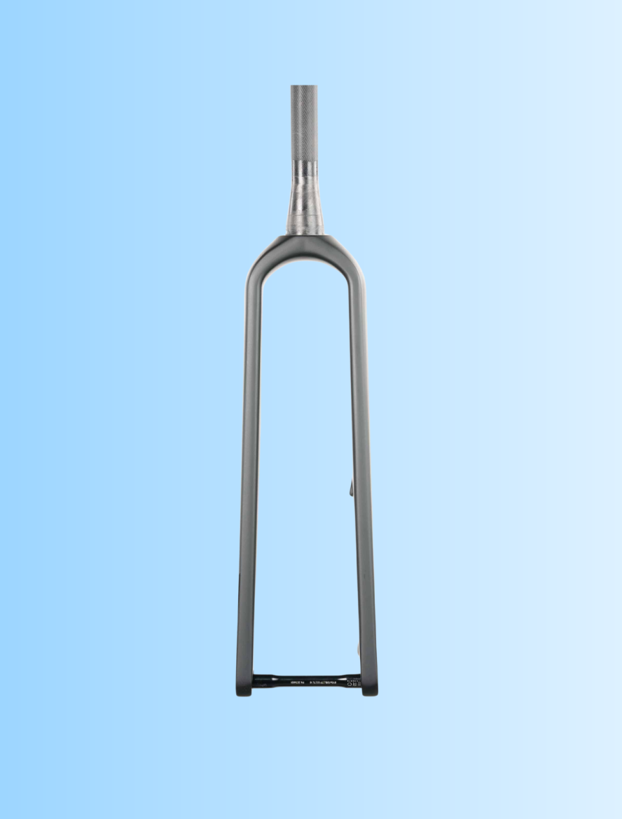 A close-up view of a bicycle fork against a light blue gradient background. The fork is metallic gray, featuring a tapered design with a smooth finish and a flat base. The image focuses on the fork's structure and contours.