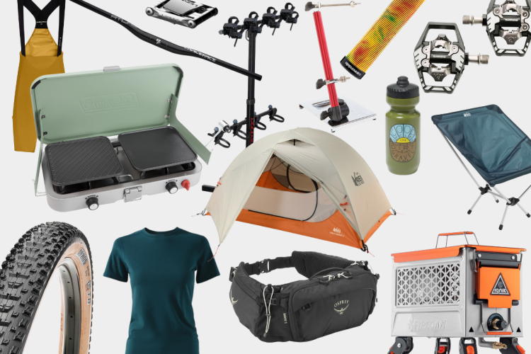 A collection of outdoor gear and equipment, including a camping stove, a two-person tent, a bike tire, a t-shirt, a water bottle, a backpack, a folding chair, bike pedals, and a portable campfire. The items are arranged on a light background, showcasing essential gear for camping and biking enthusiasts.