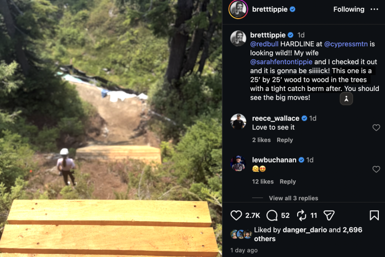 A scenic view from a wooden ramp, looking down a slope surrounded by trees and greenery. A person in a helmet stands at the edge of the ramp, ready to descend. The image conveys a sense of excitement and adventure in a mountain biking setting.
