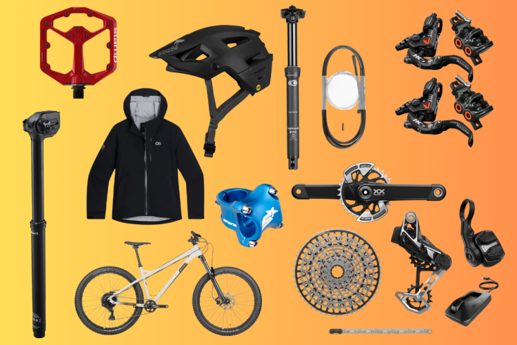 Alt text: A flat lay of various mountain biking gear and accessories on a gradient orange background, including a red pedal, black helmet, black jacket, dropper seat post, bike frame, blue handlebar grips, and several components like a chain, derailleur, and cassette.