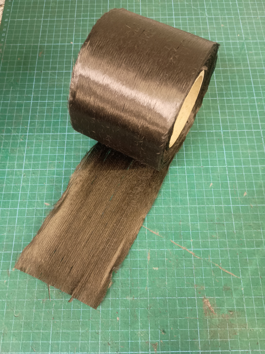 Roll of black material unrolling on a green cutting mat with a grid pattern.