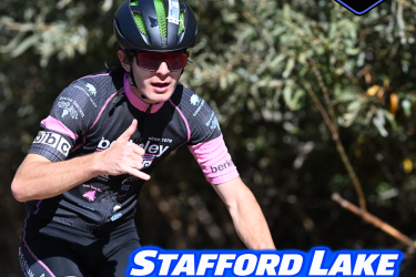 A mountain biker wearing a black and pink jersey does a hand gesture while riding on a trail surrounded by greenery. The background features the text "November 8, 2026" and promotional details for the "Stafford Lake Rattler XC + Juniors Fundraiser."
