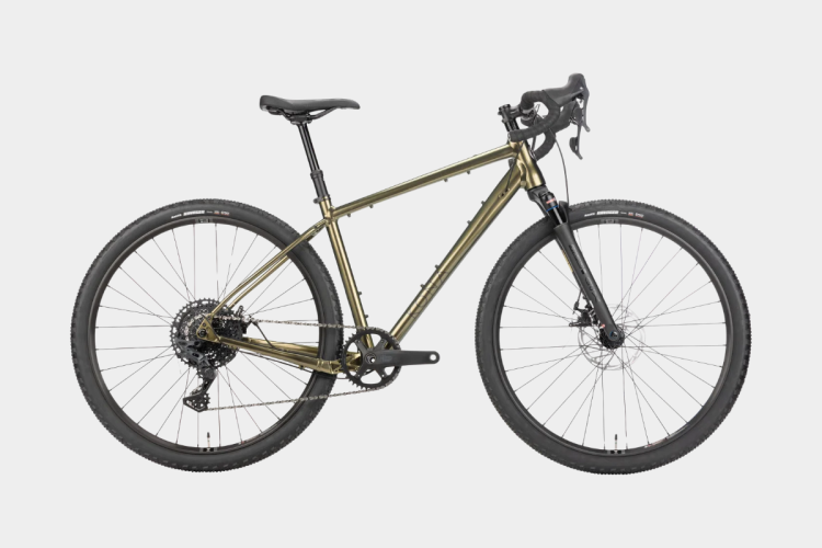 A sleek, olive-colored gravel bike with a lightweight frame, drop handlebars, and wide tires for off-road performance. The bike features a prominent suspension fork and a modern drivetrain, designed for versatility and durability on various terrains.